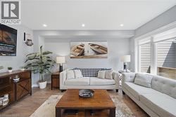 Open living space featuring wood-finish flooring, recessed lighting, and large windows - 