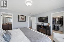 Comfortable bedroom with soft gray walls, neutral carpeting, and a modern flush-mount ceiling light - 
