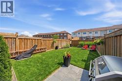 Expansive backyard featuring a lush lawn, privacy fencing, a paver patio area, and mature landscaping - 