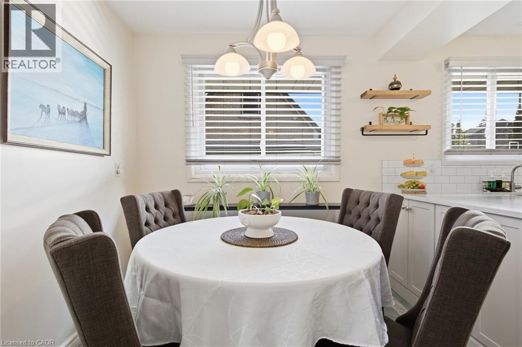 Dining area featuring a contemporary chandelier, multiple windows with blinds, a white subway tile backsplash, light-toned cabinetry, and open shelving - 11 Summit Crescent, Guelph, ON - Indoor Photo Showing Dining Room