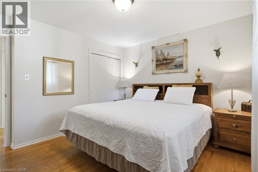 Bright interior room featuring wood-finish flooring, white walls, and a built-in closet with white doors - 11 Summit Crescent, Guelph, ON - Indoor Photo Showing Bedroom
