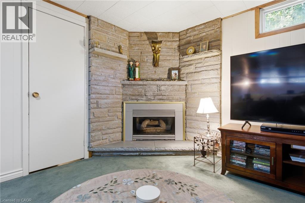 Corner fireplace with a stone surround and hearth, featuring a metal firebox insert - 11 Summit Crescent, Guelph, ON - Indoor Photo Showing Living Room With Fireplace