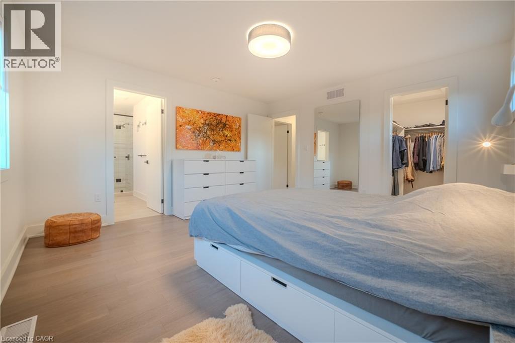 Spacious bedroom featuring light wood-finish flooring, recessed lighting, and an ensuite bathroom entry with a glass-enclosed shower - 9 Princeton Common, St. Catharines, ON - Indoor Photo Showing Bedroom