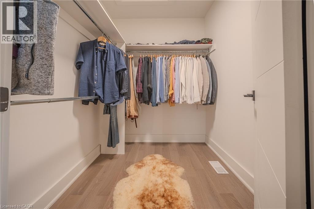 Walk-in closet featuring light wood-finish flooring, white walls, and built-in metal hanging rods - 9 Princeton Common, St. Catharines, ON - Indoor With Storage