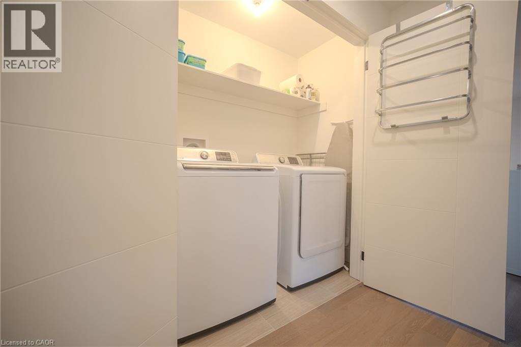 Dedicated laundry space featuring a white washer and dryer pair, recessed shelving, and tiled flooring - 9 Princeton Common, St. Catharines, ON - Indoor Photo Showing Laundry Room