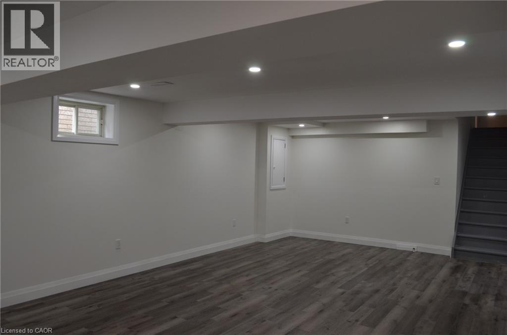 Finished lower-level space featuring recessed lighting, wood-finish flooring, white baseboards, and a window with a white frame - 275 Locheed Drive Unit# Lower, Hamilton, ON - Indoor