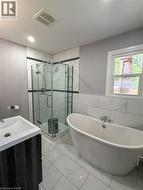 Main floor bathroom Freestanding soaking tub with chrome fixtures, complemented by a glass-enclosed corner shower - 