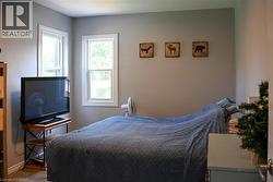 Main floor bedroom featuring two windows with white trim, light gray walls, and wood-finish flooring - 