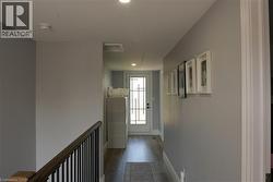 Hallway with light gray walls, recessed lighting, and wood-finish flooring - 