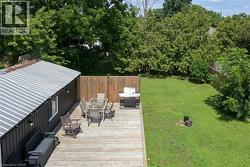 Expansive backyard featuring a wood deck, manicured lawn, wood fencing, and mature trees - 