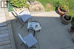 Concrete patio area featuring a wooden deck border, natural rock landscaping, and planted greenery - 