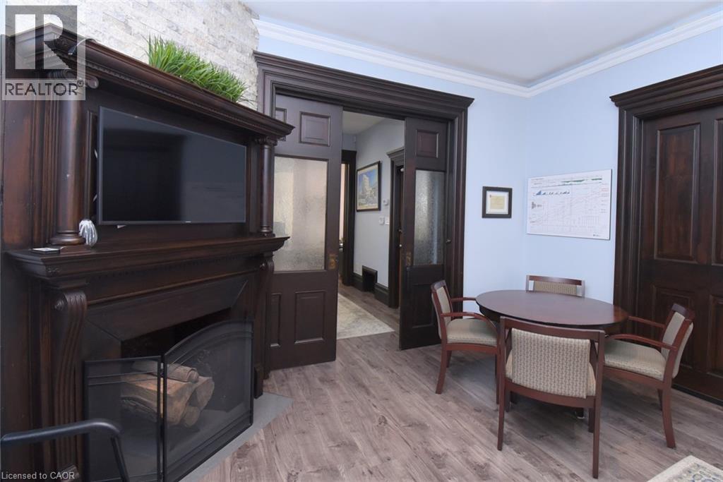 Ornate wood-finish fireplace mantel with decorative corbels and pillars, set against a stacked stone accent wall - 108 George Street, Hamilton, ON