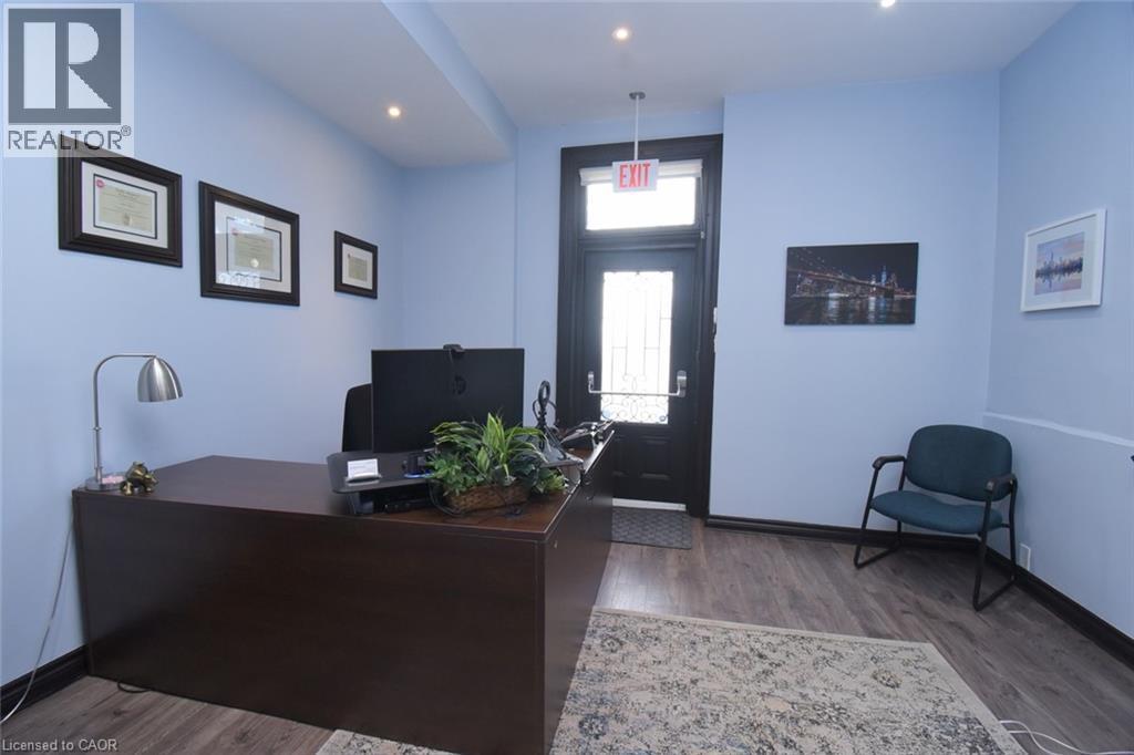 Entry area featuring wood-finish flooring, recessed lighting, and a dark-toned door with a glass insert - 108 George Street, Hamilton, ON