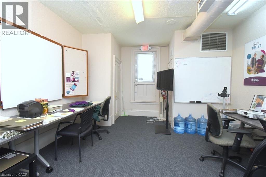 Carpeted interior space featuring multiple wall-mounted whiteboards, built-in shelving, and exposed ceiling ductwork - 108 George Street, Hamilton, ON