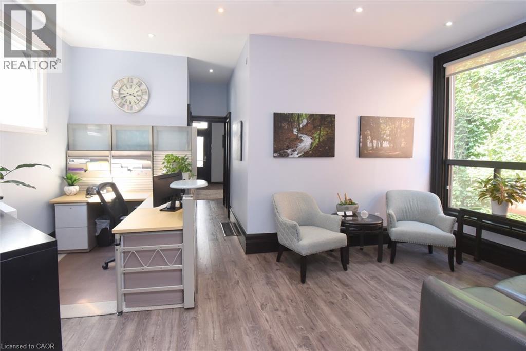 Open-concept interior featuring wood-finish flooring, recessed lighting, and a large window with exterior foliage - 108 George Street, Hamilton, ON