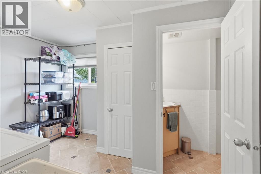 Utility space featuring durable tile flooring, a window providing natural light, and a white paneled door - 432 Upper Sherman Avenue, Hamilton, ON - Indoor Photo Showing Laundry Room