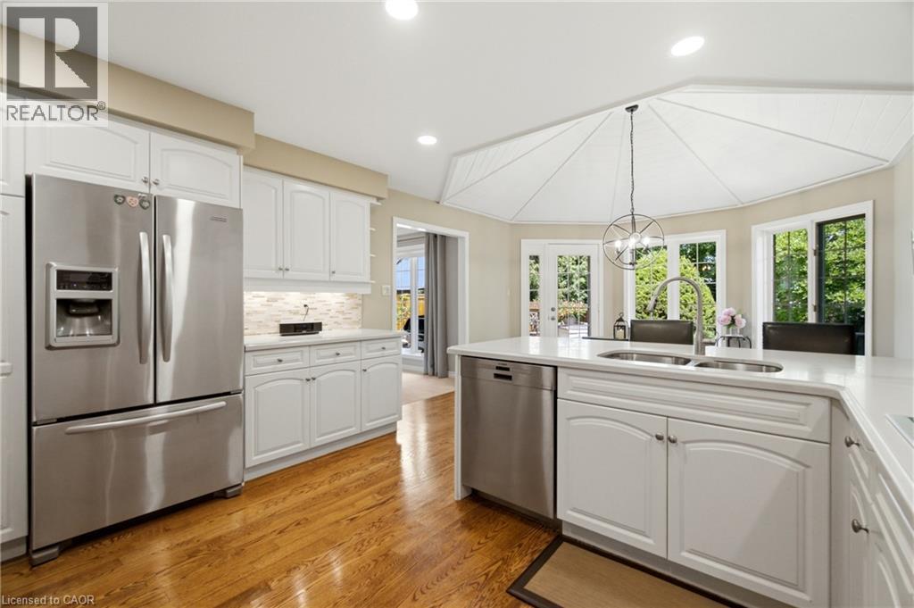 Kitchen featuring wood-finish flooring, white cabinetry, stainless steel appliances, and a central island with a double basin sink - 1090 Crofton Way, Burlington, ON - Indoor Photo Showing Kitchen With Stainless Steel Kitchen With Double Sink