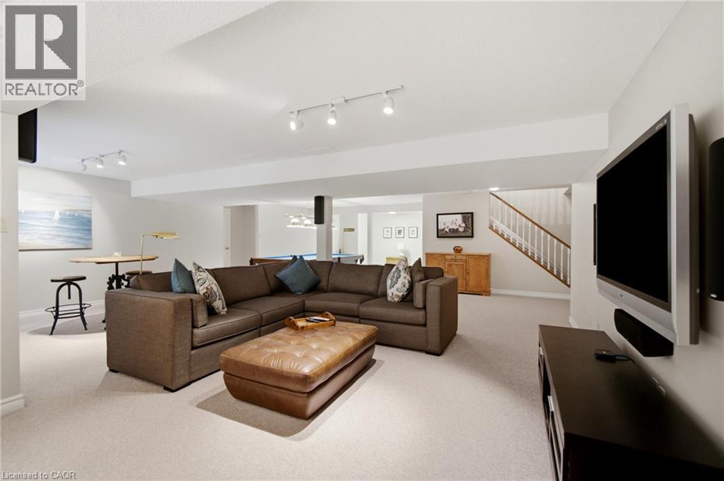 Spacious lower-level area featuring light-toned carpeting and track lighting - 1090 Crofton Way, Burlington, ON - Indoor Photo Showing Living Room