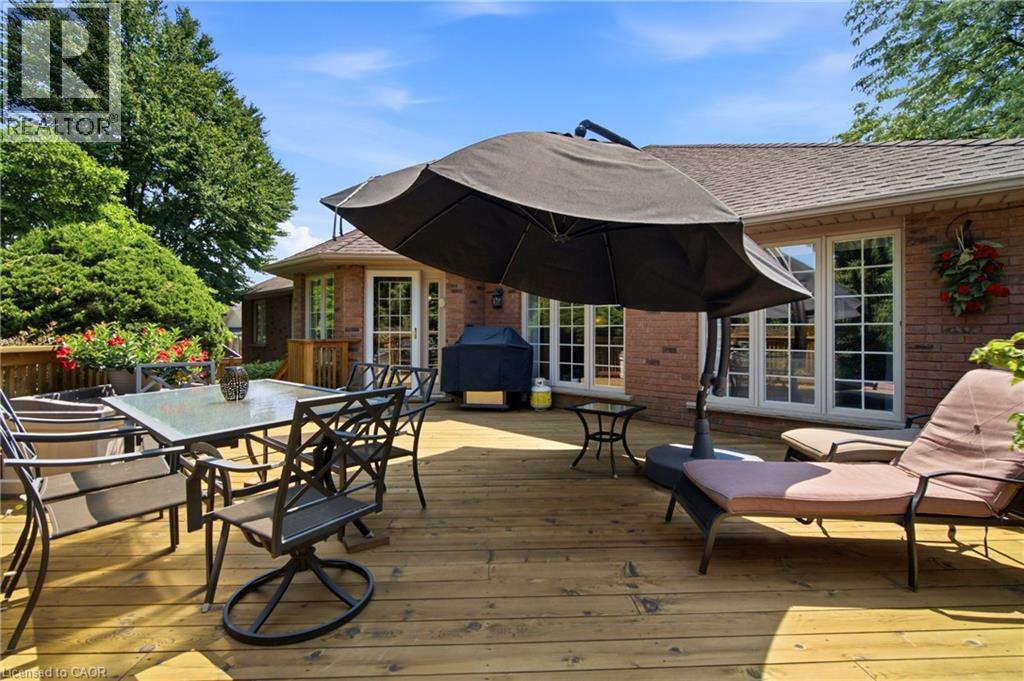 Spacious wood-finish deck featuring a red brick exterior, multiple sets of French doors, and mature perimeter landscaping - 1090 Crofton Way, Burlington, ON - Outdoor With Deck Patio Veranda With Exterior