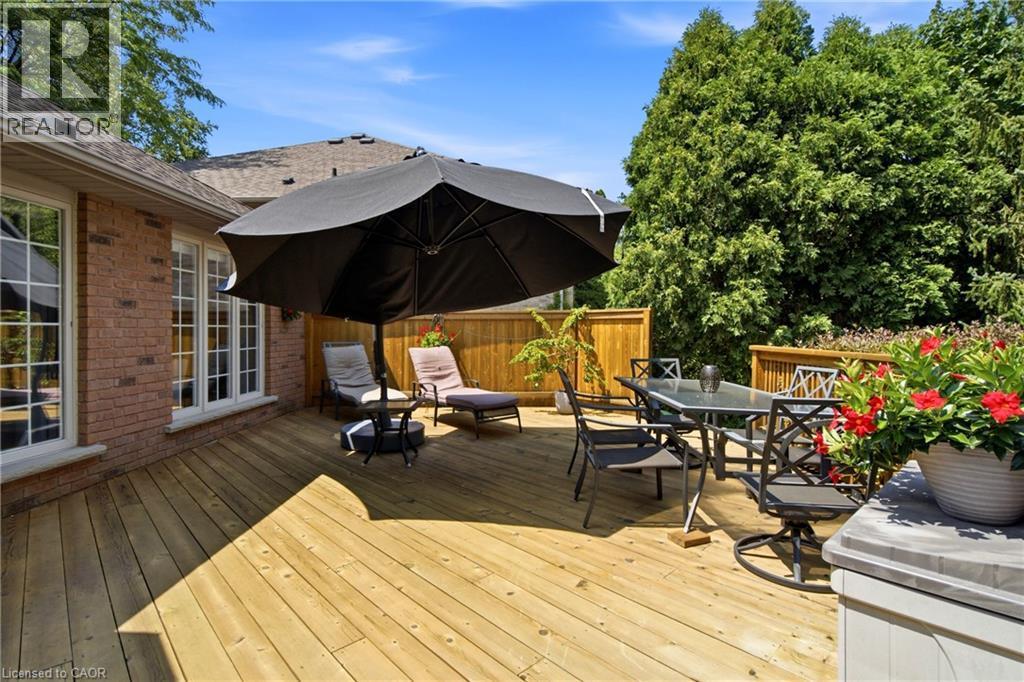 Expansive wood deck with a privacy fence, featuring a brick exterior with multiple windows, and dense evergreen landscaping - 1090 Crofton Way, Burlington, ON - Outdoor With Deck Patio Veranda With Exterior