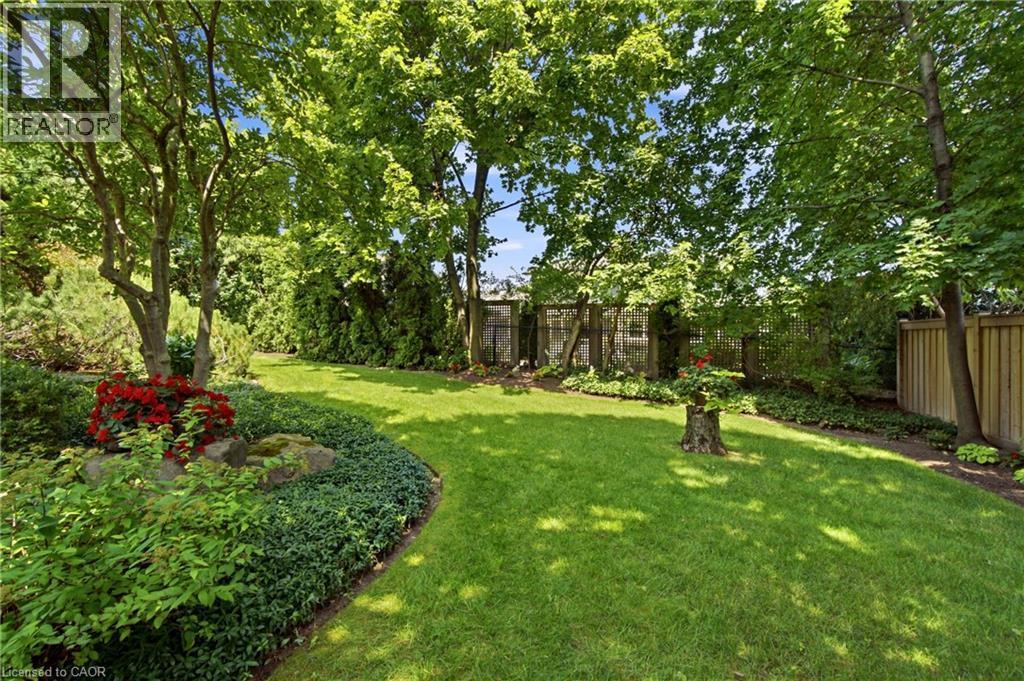 Expansive rear yard featuring a manicured lawn, established trees, mature perimeter plantings, and natural wood fencing - 1090 Crofton Way, Burlington, ON - Outdoor
