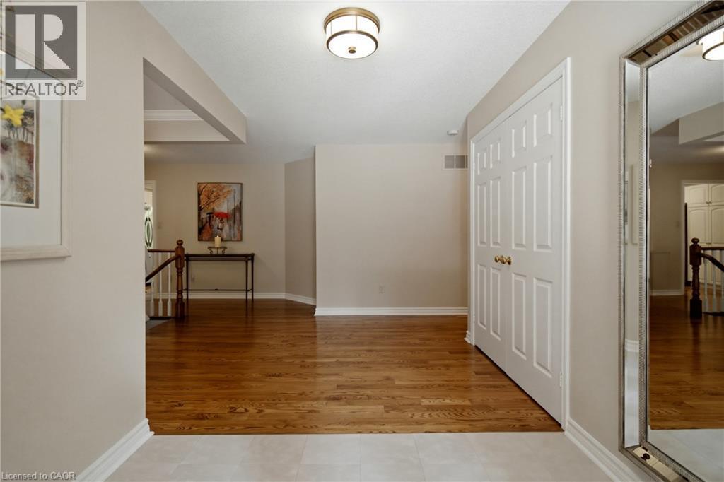 Bright entry foyer featuring a two-tone floor with tile and wood-finish flooring, a ceiling-mounted light fixture, and a paneled double-door closet - 1090 Crofton Way, Burlington, ON - Indoor Photo Showing Other Room