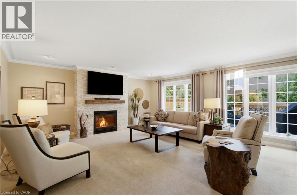 Living room featuring a stacked stone fireplace with a wood mantle, recessed lighting, crown molding, and large windows with grid patterns - 1090 Crofton Way, Burlington, ON - Indoor Photo Showing Living Room With Fireplace