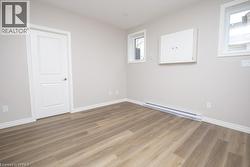 Versatile room featuring wood-finish flooring, light grey walls, and white trim - 