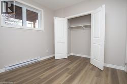 Room featuring wood-finish flooring, light grey painted walls, and white baseboards - 