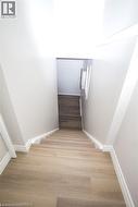 Staircase featuring wood-finish flooring, white risers, and white baseboards - 