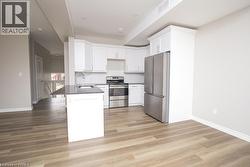 Kitchen featuring white cabinetry, stainless steel appliances, a dark countertop, and an island with an undermount sink - 