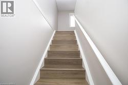 Staircase featuring wood-finish treads, white risers, and a white handrail - 
