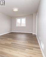 Room featuring light wood-finish flooring, light gray wall paint, and white trim - 