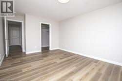 Spacious room featuring wood-finish flooring, light gray wall paint, and white baseboards - 
