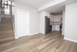 Open-concept room featuring wood-finish flooring, light grey wall paint, and white trim - 