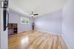 Bright room featuring wood-finish flooring, a white-framed window, a ceiling fan, and white baseboards - 