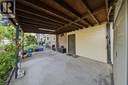 Covered outdoor space featuring a concrete pad and exposed wood beam ceiling - 