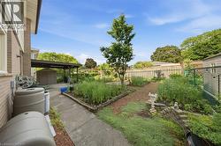 Expansive backyard featuring a concrete pathway, a covered patio area, a detached storage shed, raised garden beds, and mature perimeter fencing - 