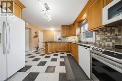 Kitchen featuring light wood cabinetry, checkerboard tile flooring, stainless steel range, and stone-look countertops - 