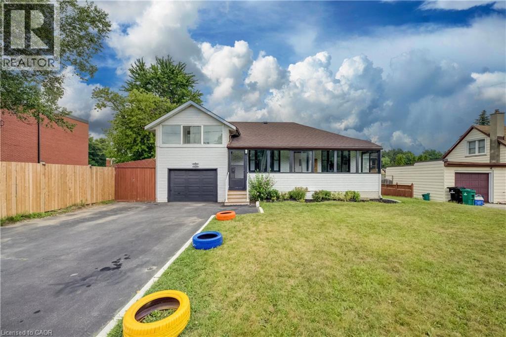 Front exterior featuring white siding, a dark asphalt shingle roof, and a single-car garage with a dark door - 182 Avalon Place, Kitchener, ON - Outdoor