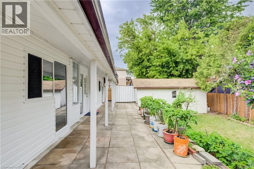 Expansive rear patio featuring concrete pavers, a white vinyl-sided exterior, and a covered porch - 182 Avalon Place, Kitchener, ON - Outdoor