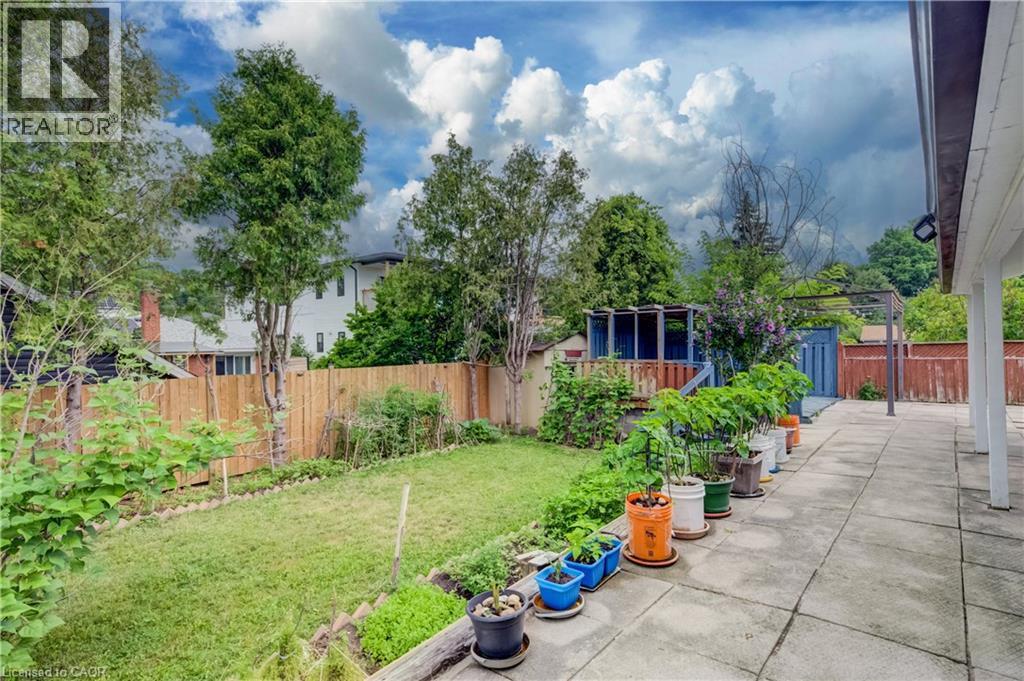 Spacious backyard featuring a large concrete patio, manicured lawn, and a wooden privacy fence - 182 Avalon Place, Kitchener, ON - Outdoor