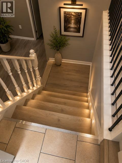Staircase featuring wood-finish treads with integrated step lighting and a white baluster railing - 143 Grenfell Place, London, ON - Indoor Photo Showing Other Room