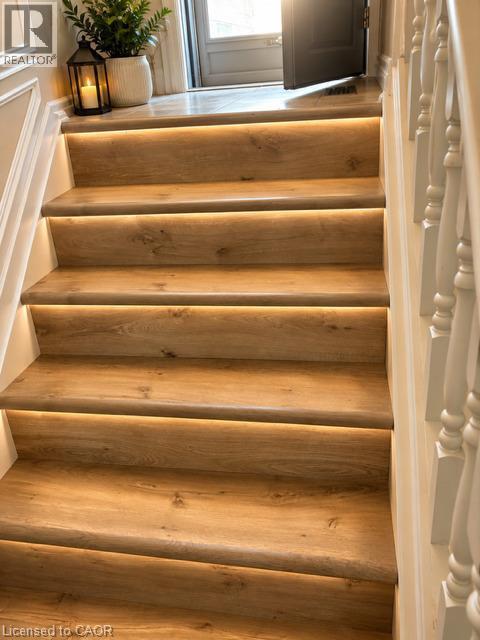 Staircase featuring wood-finish treads with integrated strip lighting, white risers, and a white baluster railing - 143 Grenfell Place, London, ON - Indoor Photo Showing Other Room