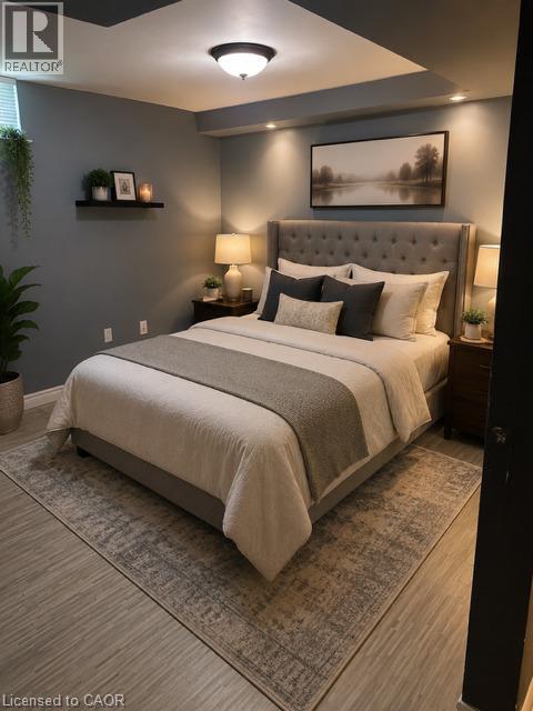 Tufted fabric headboard with integrated recessed lighting, wood-finish flooring, and a flush-mount ceiling light - 143 Grenfell Place, London, ON - Indoor Photo Showing Bedroom