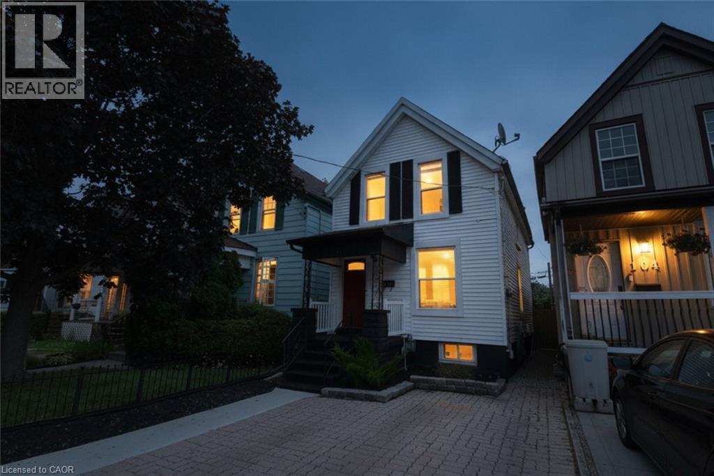 White siding exterior with black shutters, a covered entry, and a paver driveway - 106 Belview Avenue, Hamilton, ON - Outdoor With Facade