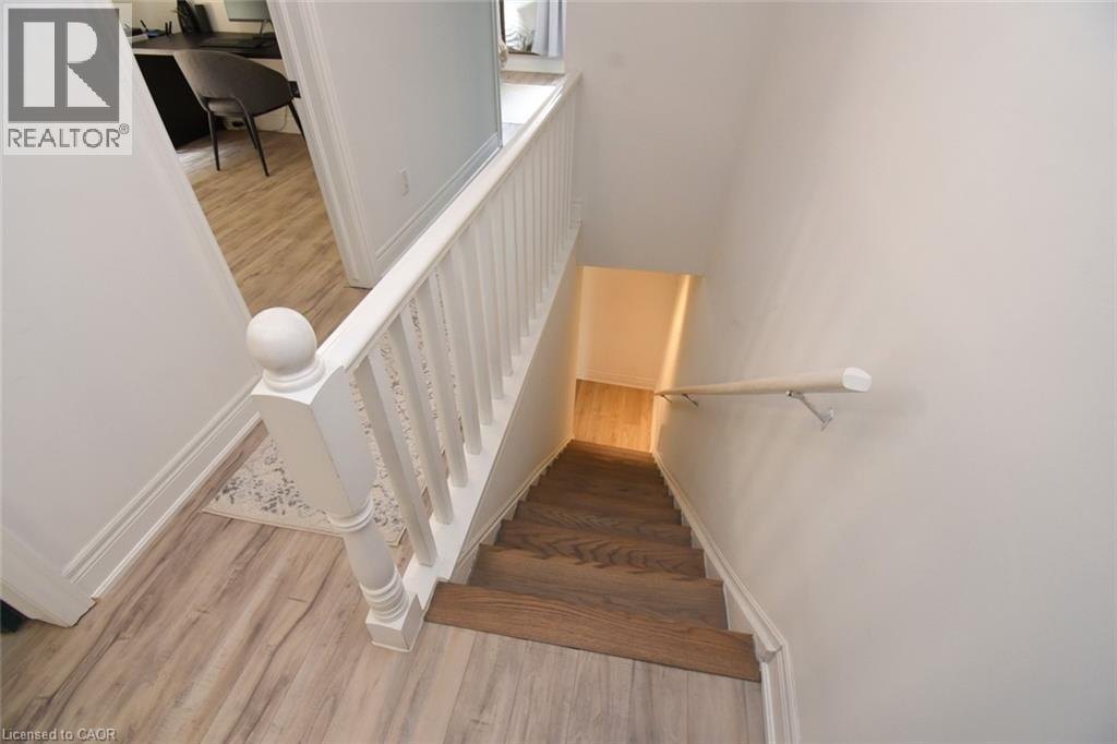 Stairwell featuring wood-finish treads, a white painted banister with square spindles and a spherical newel post, and a contrasting light wood-finish handrail - 106 Belview Avenue, Hamilton, ON - Indoor Photo Showing Other Room