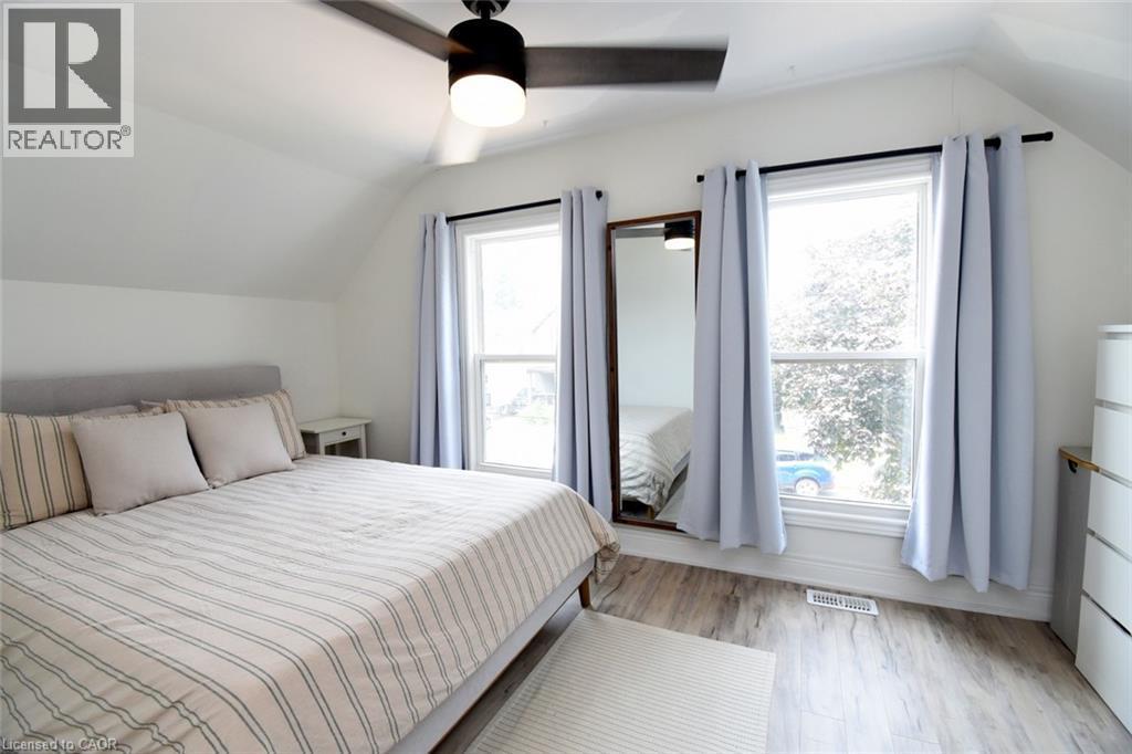 Bright room featuring wood-finish flooring, a contemporary ceiling fan, and multiple windows - 106 Belview Avenue, Hamilton, ON - Indoor Photo Showing Bedroom