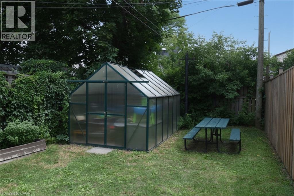 Rear yard featuring a freestanding greenhouse, a picnic table, and perimeter fencing - 106 Belview Avenue, Hamilton, ON - Outdoor