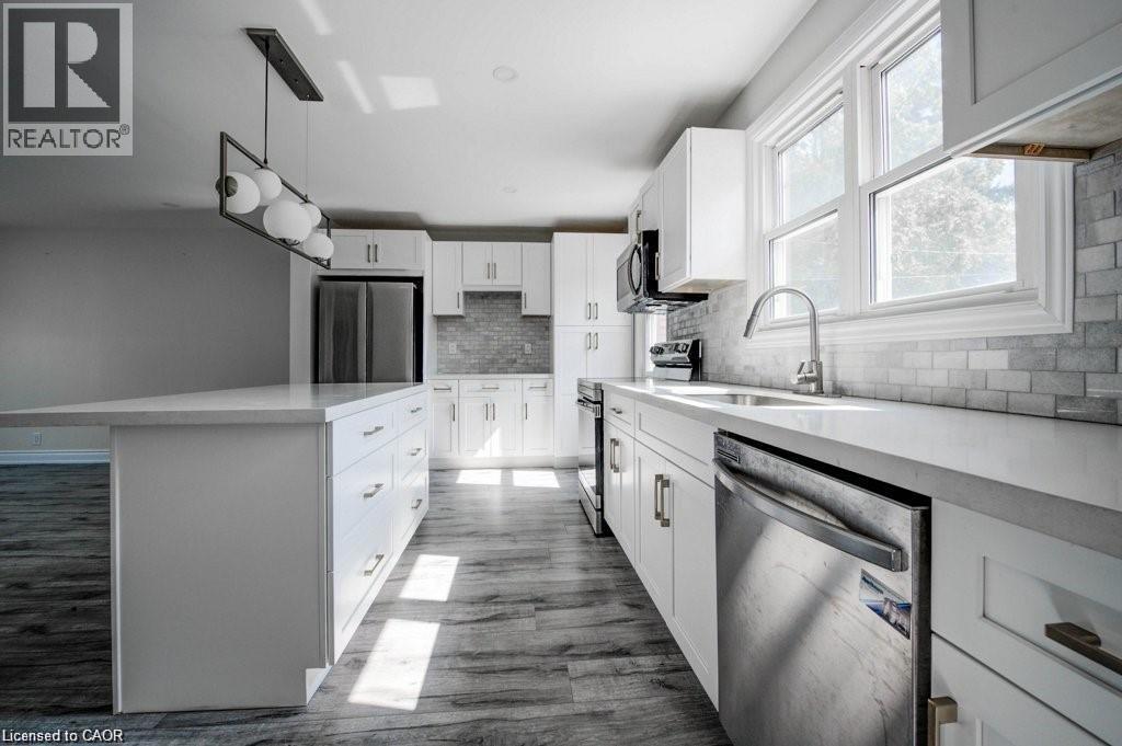 Kitchen featuring an oversized island with a white countertop, white shaker-style cabinetry with brushed nickel hardware, and wood-finish flooring - 33 Sixth Avenue Unit# Upper, Kitchener, ON - Indoor Photo Showing Kitchen With Upgraded Kitchen